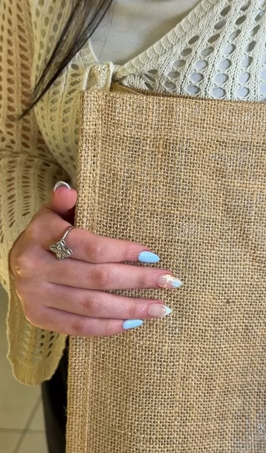 Soft blue and white nails against a knit sleeve